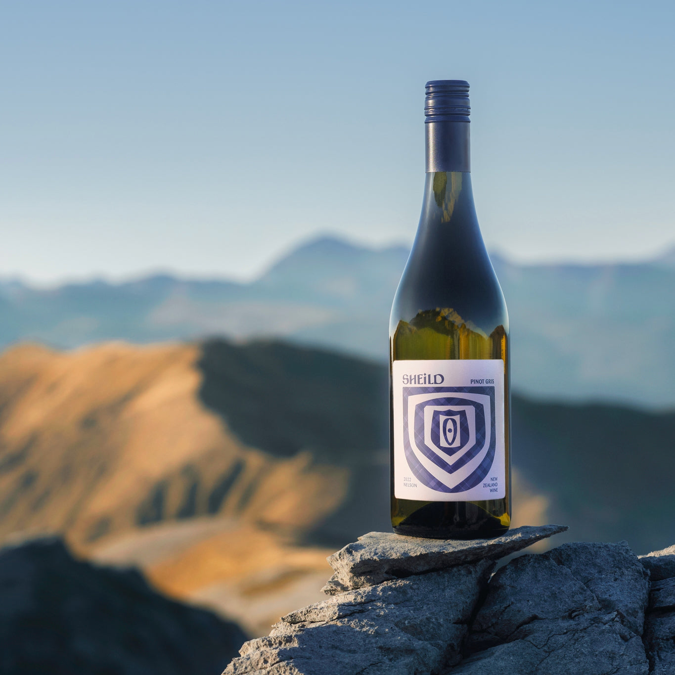 SHEiLD's Pinot Gris wine placed on a rock atop a mountain on a sunny day.